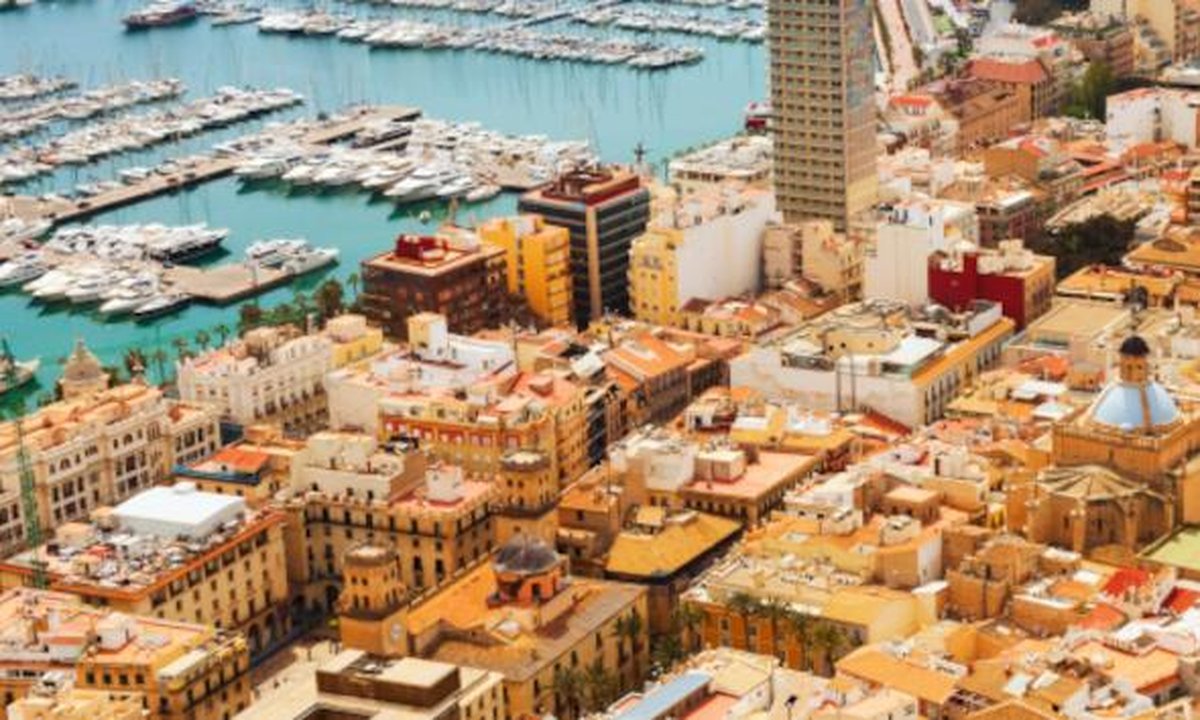 Tourists relaxing on Postiguet Beach in Alicante with Santa Bárbara Castle background